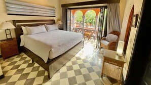 A bedroom with a bed, bedside table, lamp, and a view of an outdoor patio with chairs and a table. - Villa Cerca Del Mar #6- 3BR House with Pool (Langosta)