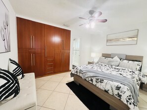 A bedroom with a bed, a wardrobe, a ceiling fan, and a nightstand.