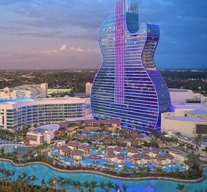 A large hotel with a guitar-shaped building, multiple swimming pools, and a resort area with villas.