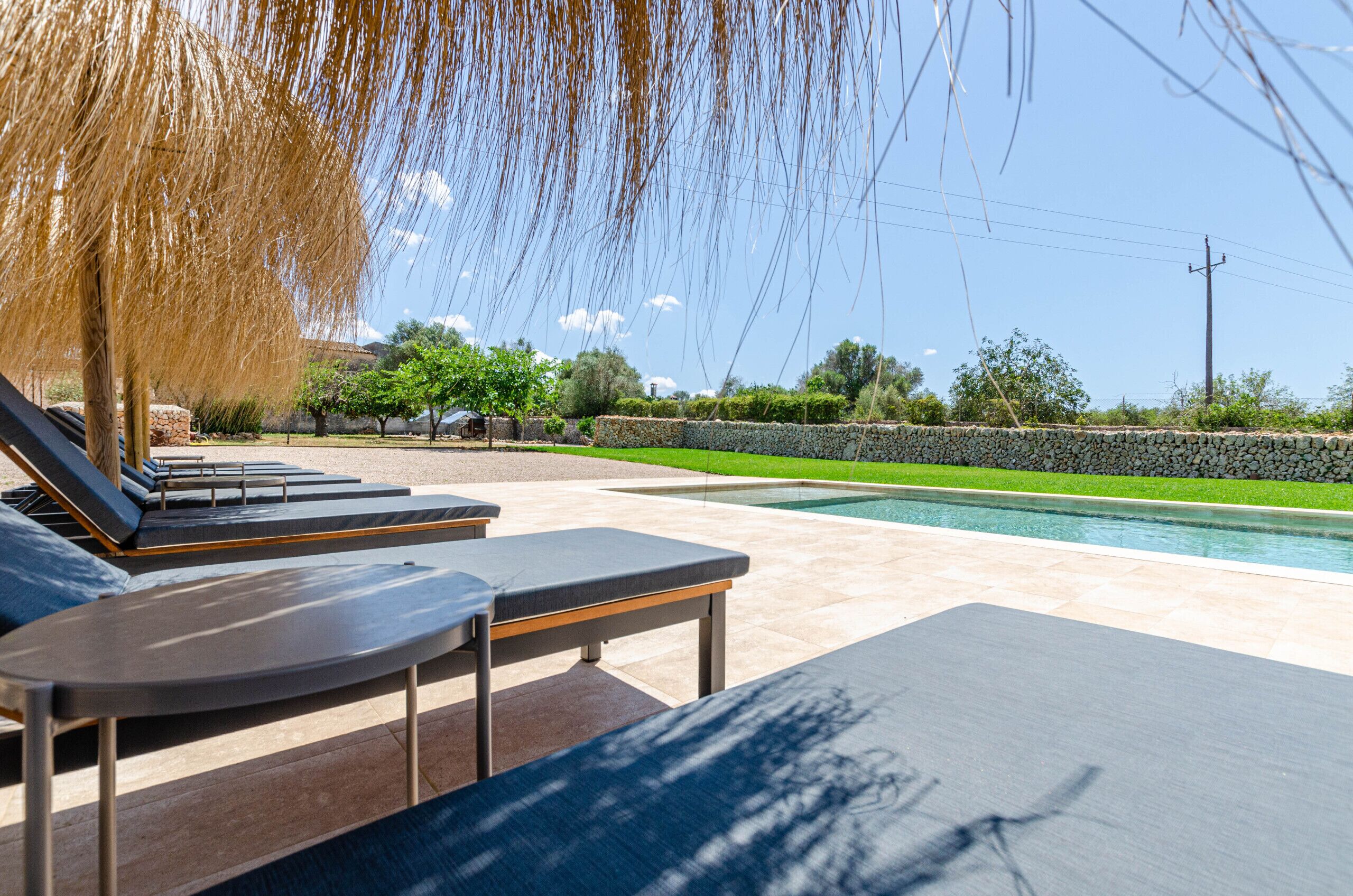 A poolside area with lounge chairs, a stone wall, and a clear view of the pool.