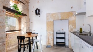 A kitchen with a wooden table, chairs, a broom, and a sink.
