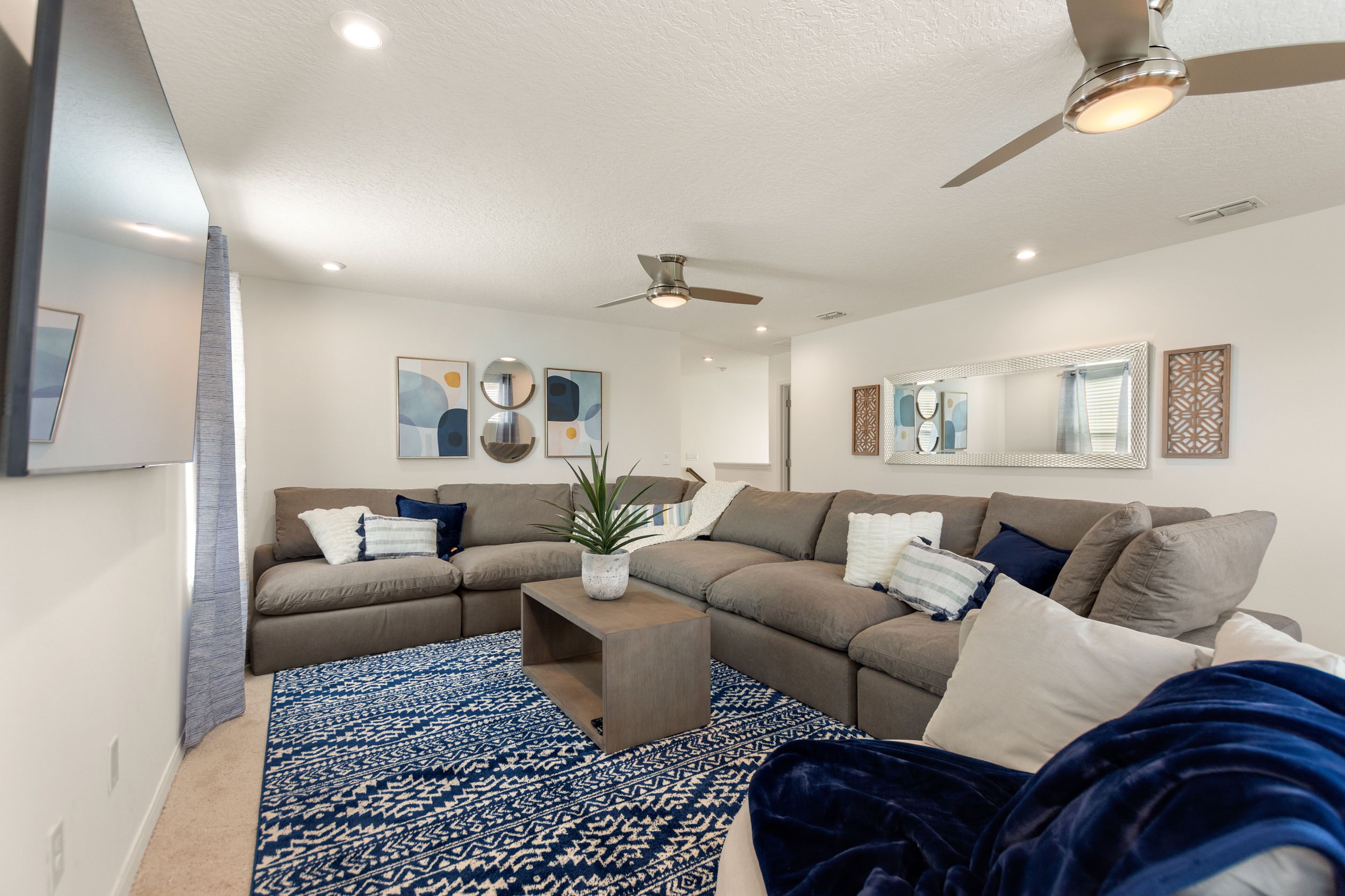 A modern living room with a sectional sofa, a coffee table, and a ceiling fan.