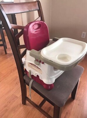 A portable toilet unit sits on a chair, featuring a lid and red accents.