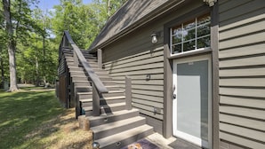 A wooden building with a gray exterior, a set of stairs leading to a door, and a welcome mat with a dog illustration. - Chickahominy Riverside Guest Home 30 Minutes to Williamsburg! (Charles City)