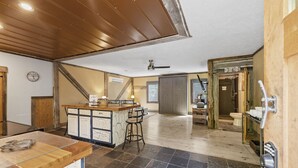 A spacious kitchen with a central island, a dining area with a wooden table, and a view of the bathroom. - Chickahominy Riverside Guest Home 30 Minutes to Williamsburg! (Charles City)