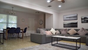 A spacious living room with a grey sofa, a coffee table, and a dining area with chairs and a table. - Arlington Park Area! 3BR/2BA Sarasota Home – Heated Large Pool (Sarasota)