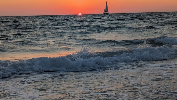 A sunset over the ocean with a sailboat in the distance. - Arlington Park Area! 3BR/2BA Sarasota Home – Heated Large Pool (Sarasota)