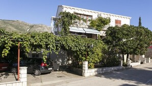 Edifici de dues plantes amb façana blanca, un balcó i un cotxe a la part frontal.
