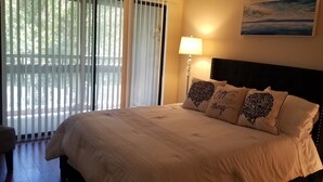 A neatly made bed with a headboard, a bedside lamp, and a painting on the wall. - Lovely Bluewater Bay 1 Bedroom Condo near Bluewater Bay Marina and Destin Island (Niceville)