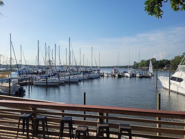 A marina with multiple boats docked, wooden deck seating, and a clear view of the water.