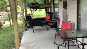 Eine Terrassenanlage im Freien mit Grill, roten Stühlen und einem Glastisch.
