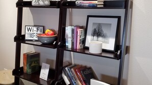 A bookshelf with books, a framed picture, a small plant, and a Wi-Fi sign. - Sunset Hills1600 sq. ft. lower-level apt.<br>(3 bedrooms, 2 king beds) (Nampa)