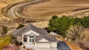 A residential property with a curved driveway, a detached garage, and a well-maintained lawn. - Sunset Hills1600 sq. ft. lower-level apt.<br>(3 bedrooms, 2 king beds) (Nampa)