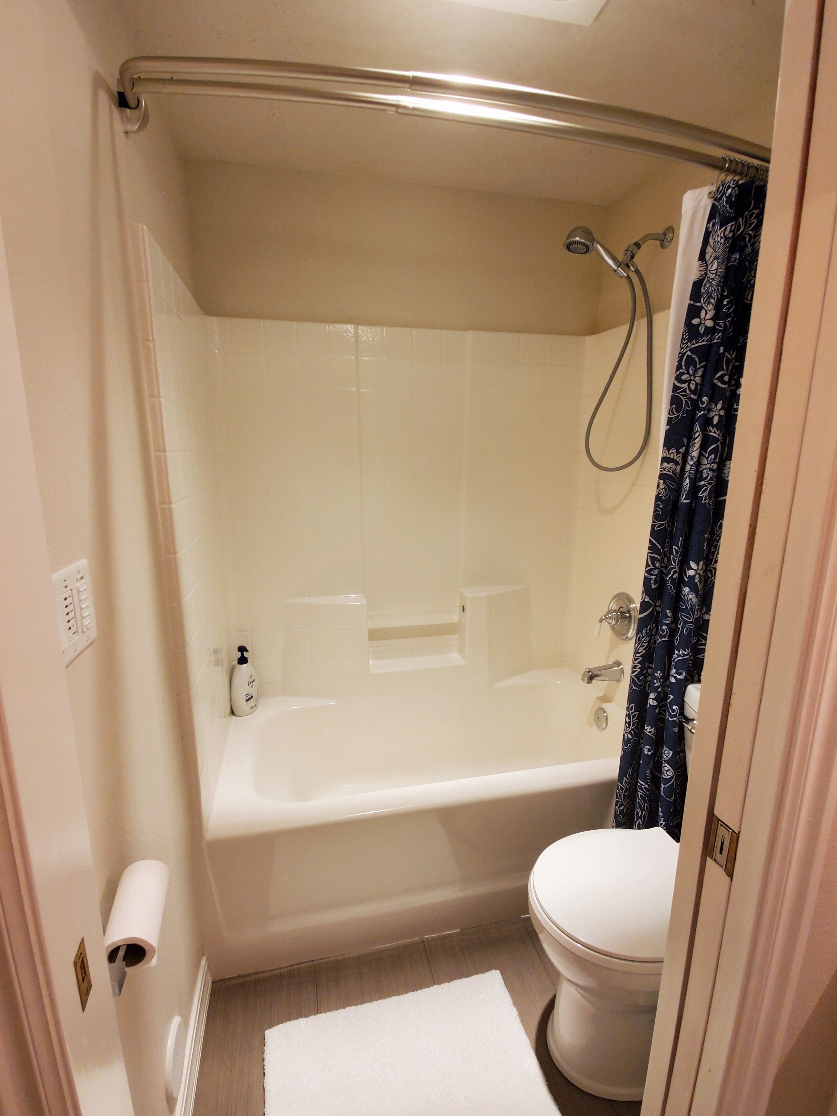 Une petite salle de bain propre, équipée d’une baignoire, de toilettes et d’un rideau de douche.