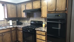Une cuisine avec des meubles de rangement en bois, une cuisinière noire, un four à micro-ondes et un four noir.