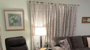 Ein Wohnzimmer mit Ledersessel, Sofa, Lampe und einem Gemälde an der Wand.