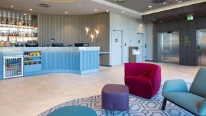 Een moderne hotellobby met een bar, zitplaatsen en een lift.