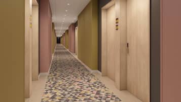 Um corredor de hotel com carpete estampado, portas de madeira e teto com iluminação embutida.