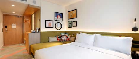 Una habitación de hotel con una cama grande, un escritorio, un armario y una pared con cuadros.