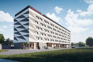 Ein modernes Hotel mit einer geometrischen Fassade, mehreren Balkonen und blauem Himmel.
