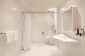A modern bathroom with a glass shower enclosure, a sink, and a mirror. - Hampton By Hilton Krakow Airport (Zabierzow)