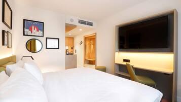 A hotel room with a large bed, a TV, a desk, and a wardrobe.