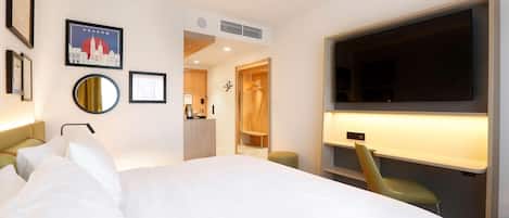 A hotel room with a large bed, a TV, a desk, and a wardrobe.