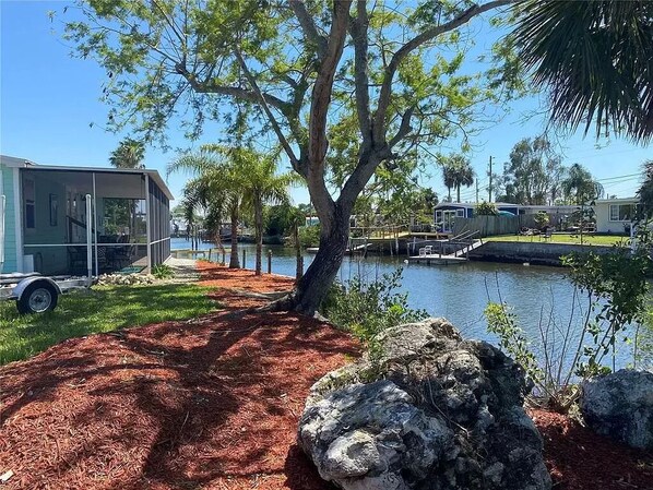 Enjoy serene lakeside views from a covered deck or patio, surrounded by lush greenery and a tranquil water body.