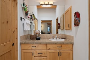 A bathroom with wooden cabinets, a sink, a mirror, and decorative items.
