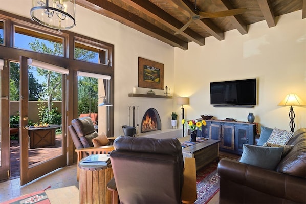 Amplia sala de estar con chimenea, muebles de cuero y un televisor grande.