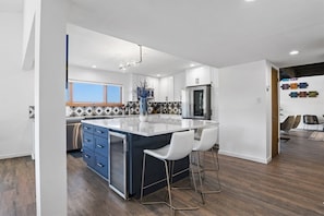 A modern kitchen with a central island, stainless steel appliances, and a view to the outside.
