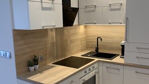 A modern kitchen with white cabinetry, a wooden countertop, a built-in oven, and a sink.