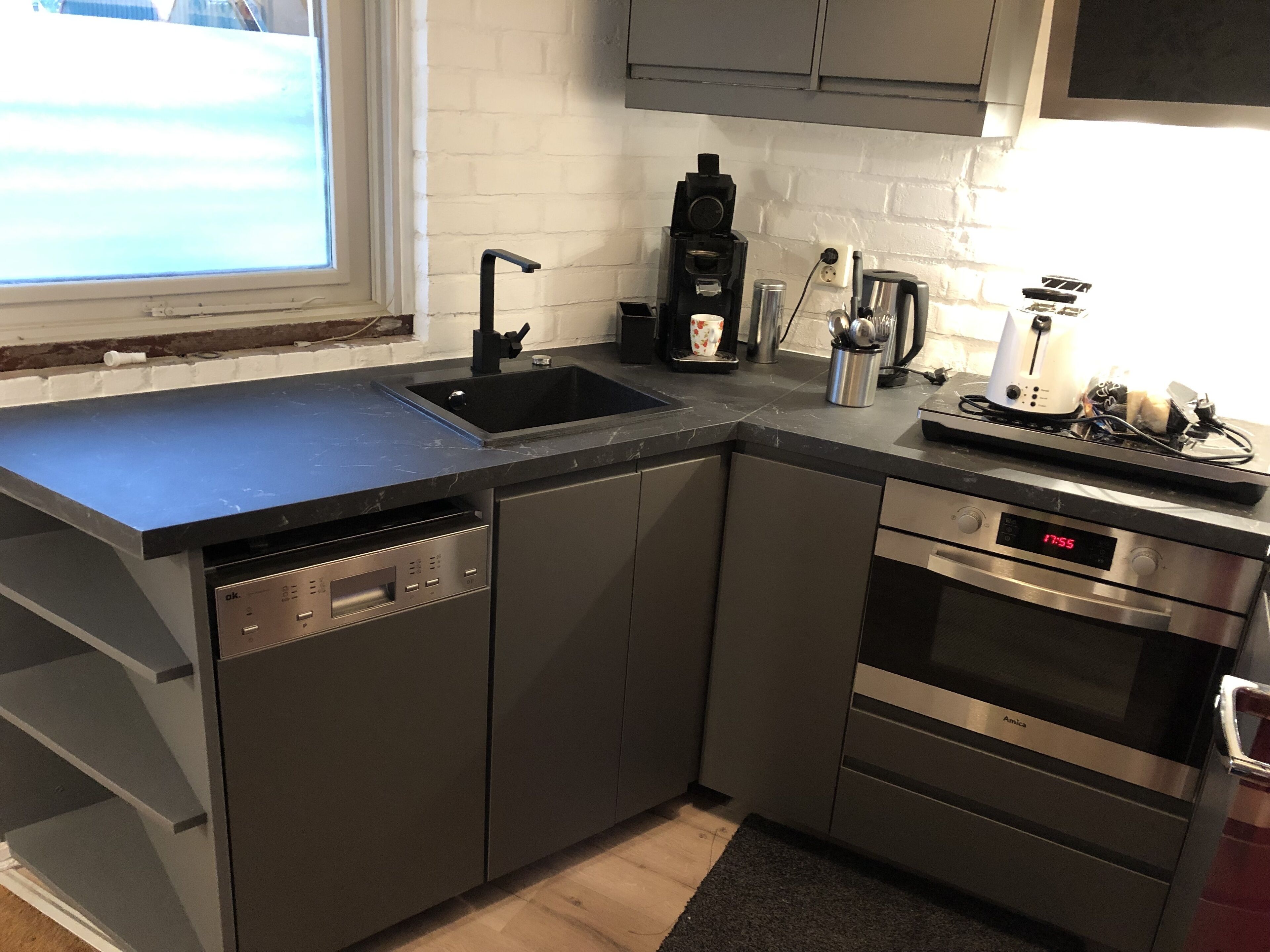 A modern kitchen with a built-in dishwasher, stainless steel appliances, and a window providing natural light.