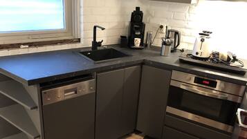 A modern kitchen with a built-in dishwasher, stainless steel appliances, and a window providing natural light.
