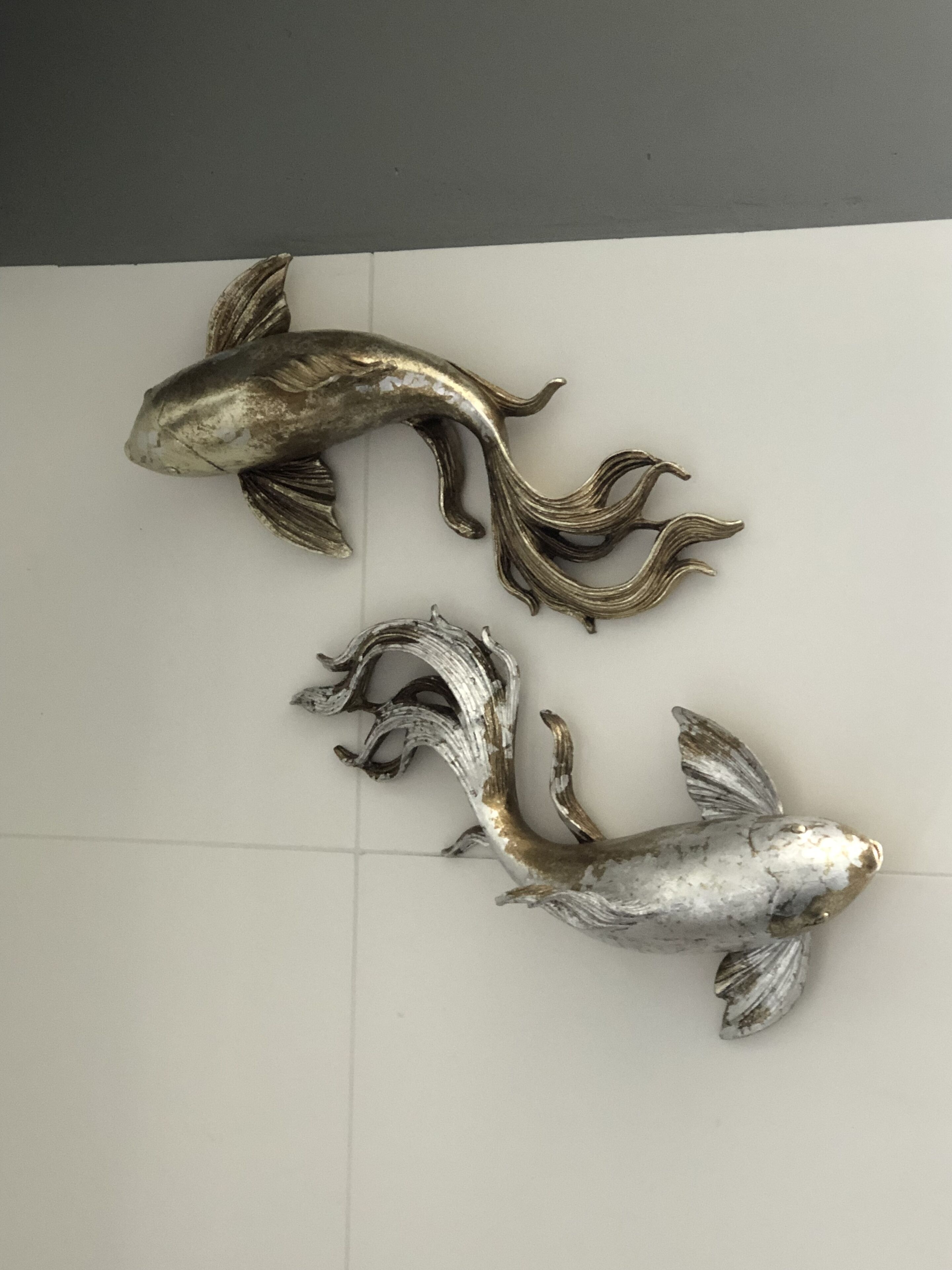 Een wandsculptuur van twee vissen.
