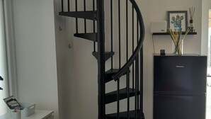 A spiral staircase with a black railing, a black refrigerator, and a framed picture on a shelf. - Cozy mini apartment on large terrace with unique view, pets allowed (Orturano)