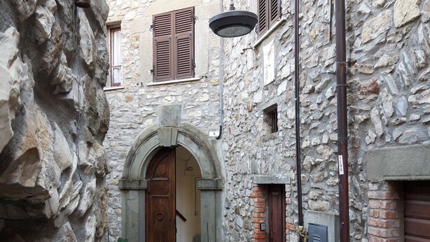 A narrow stone alleyway with a wooden door, a potted plant, and a metal lamp post. - Cozy mini apartment on large terrace with unique view, pets allowed (Orturano)