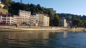 A waterfront view with buildings along the riverbank, a bridge, and a tower in the background. - Saint Vincent convent (Lyon)