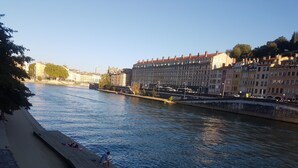 A riverside walkway with a wooden deck, a bicycle, and buildings in the background. - Saint Vincent convent (Lyon)