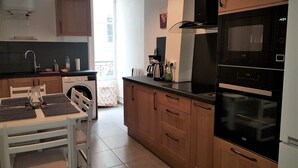 A modern kitchen with wooden cabinets, a black oven, and a coffee maker. - Saint Vincent convent (Lyon)