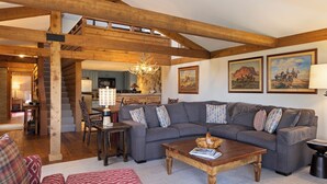 A spacious living room with a wooden ceiling, a gray sectional sofa, a wooden coffee table, and a staircase leading to an upper level. - Outpost: Golf Creek 35 - Teton Views! (Jackson)