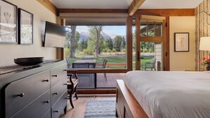 A bedroom with a large bed, a dresser, a TV, and a view of a golf course. - Outpost: Golf Creek 35 - Teton Views! (Jackson)