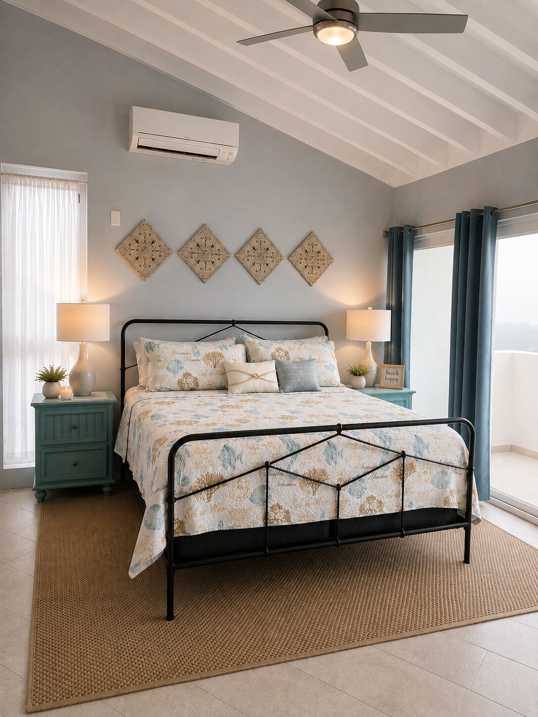 A bedroom with a bed, a ceiling fan, wall-mounted air conditioning, decorative wall art, bedside lamps, and a view through a window.