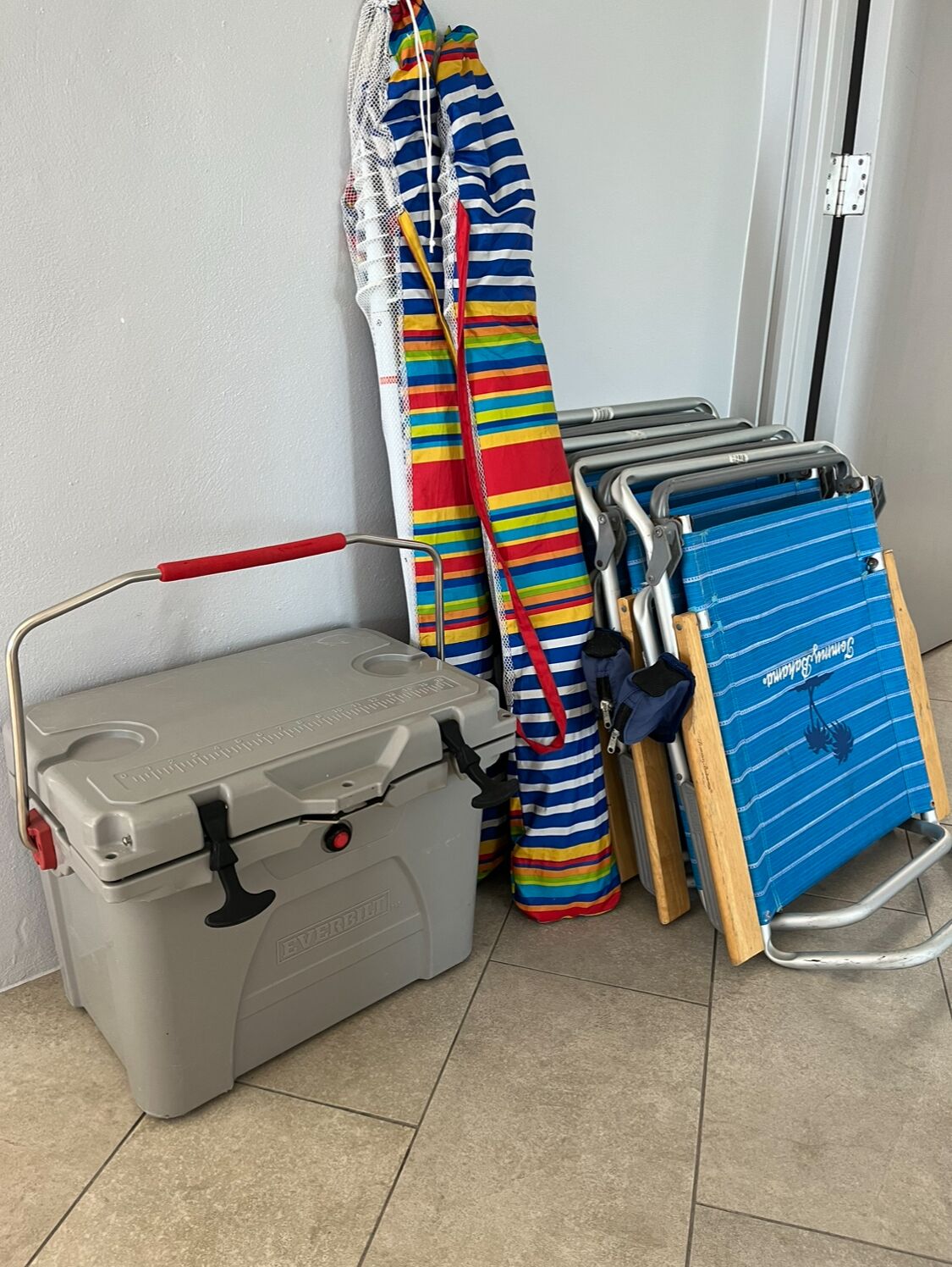 A grey storage box, a striped towel, a blue towel, and a folding chair.
