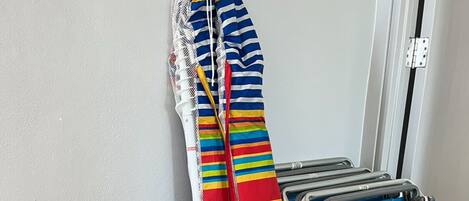 A grey storage box, a striped towel, a blue towel, and a folding chair.