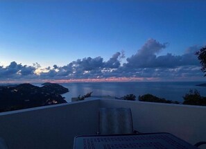 Uitzicht vanaf een balkon op een wateroppervlak met een ondergaande zon.
