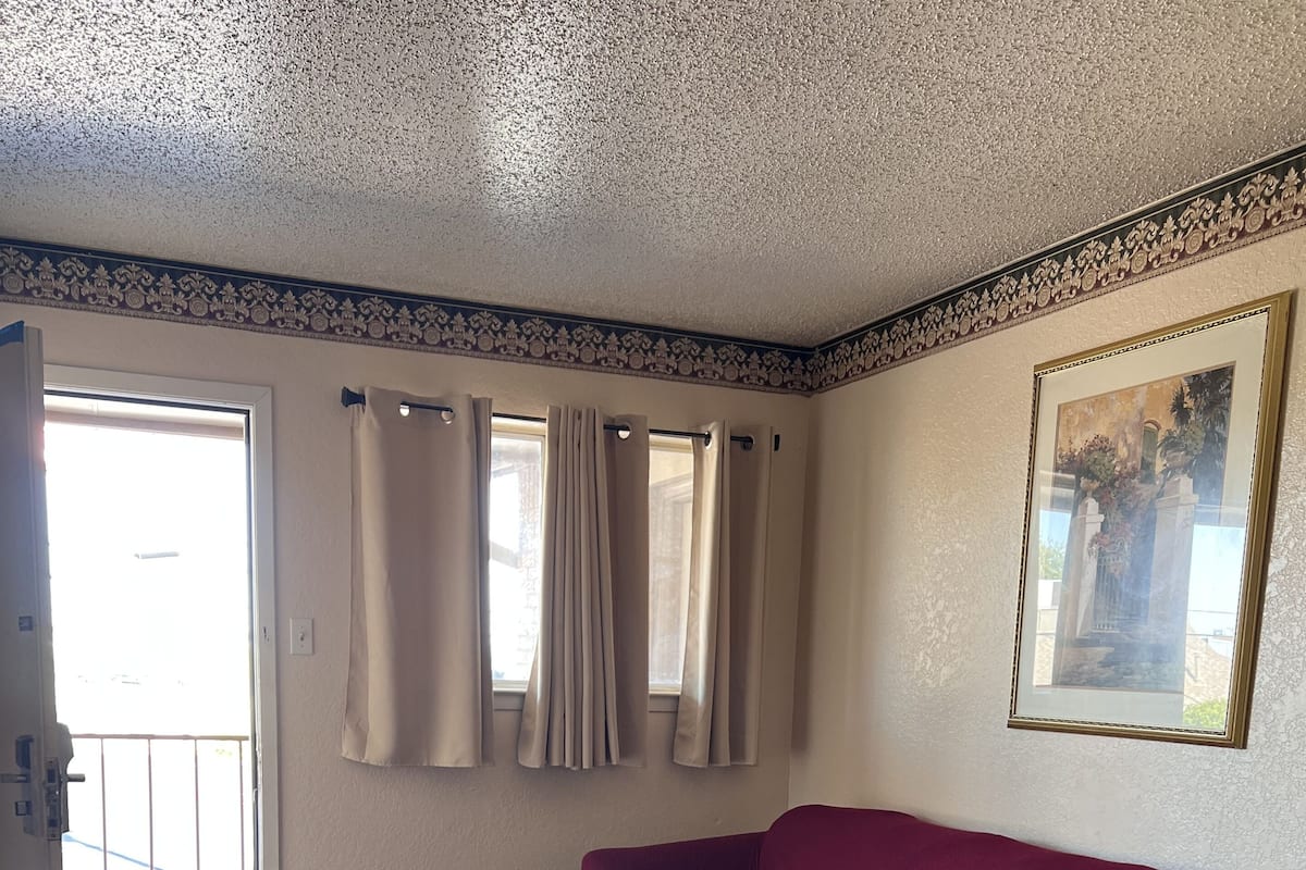 Ein Wohnzimmer mit einem roten Sofa, einem kleinen Tisch und einer Tür, die auf einen Balkon führt.