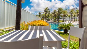 A poolside area with a white fence, palm trees, and a pool. - Apart térreo no In Mare Bali Cotovelo (Parnamirim)