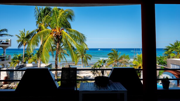 A balcony with a view of the beach, palm trees, and the ocean. - 114Night Sep/Oct Ocean Beach Front 2 Bedrooms Villa Cozumel Snorkel Scuba Diving (Cozumel)