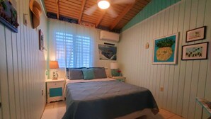 A bedroom with a bed, nightstands, a ceiling fan, and wall decorations. - Live Tropical like a local , El Yunque Rainforest View, Mountain View  (Río Grande)